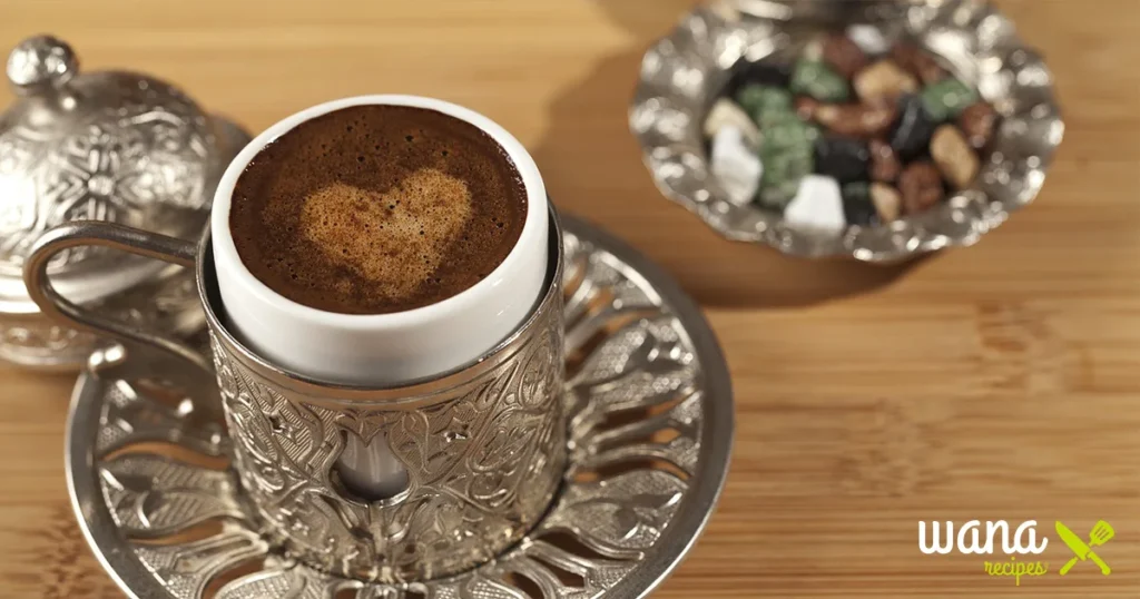 A small, traditional cup of Turkish coffee with rich crema, served with sugar cubes on a wooden tray.