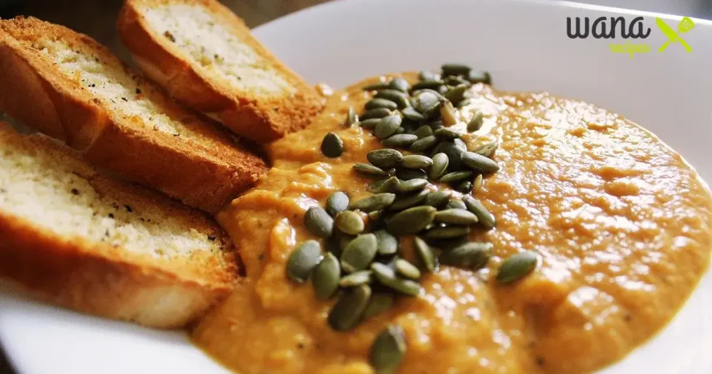 Pumpkin dip topped with seeds served with toasted bread slices.