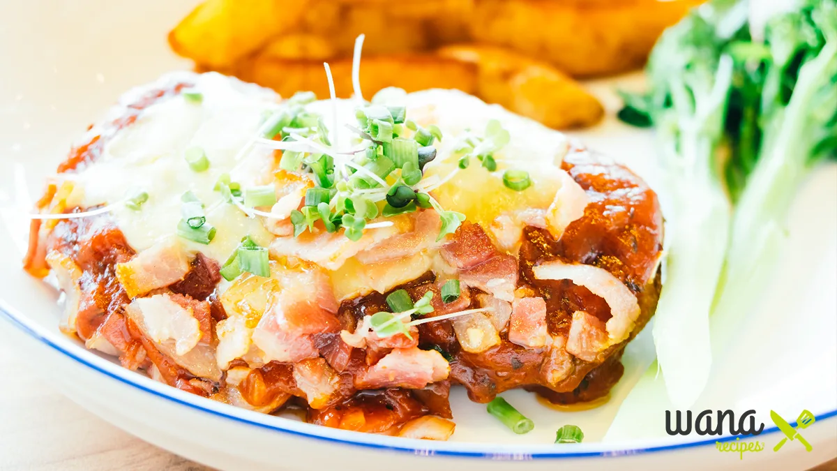 Alice Springs Chicken served on a plate with melted cheese, crispy bacon, and a side of vegetables.