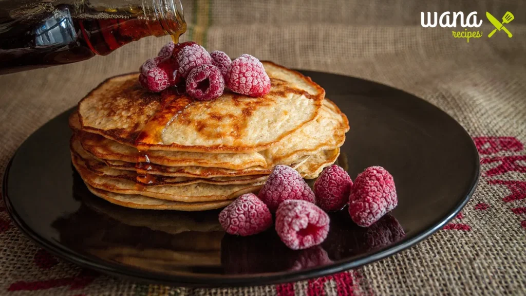 Fluffy pancakes served with syrup and fresh fruit at a community breakfast.