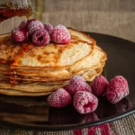 Fluffy pancakes served with syrup and fresh fruit at a community breakfast.