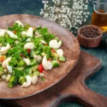 Broccoli cauliflower salad served in a white bowl with fresh vegetables, creamy dressing, and optional toppings like cherry tomatoes and nuts.