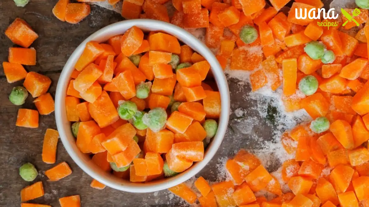 Diced carrots in a bowl surrounded by fresh vegetables, ready for cooking delicious dinner recipes.