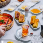 An assortment of traditional Asian breakfast dishes, including pho, nasi lemak, and dim sum, served on a wooden table.