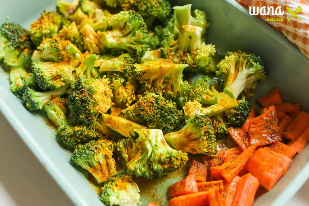 Fresh broccoli, cauliflower, red onion, and cherry tomatoes on a wooden cutting board.