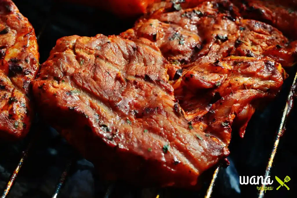 Marinated steaks grilling over an open flame, with a rich reddish-brown crust forming.