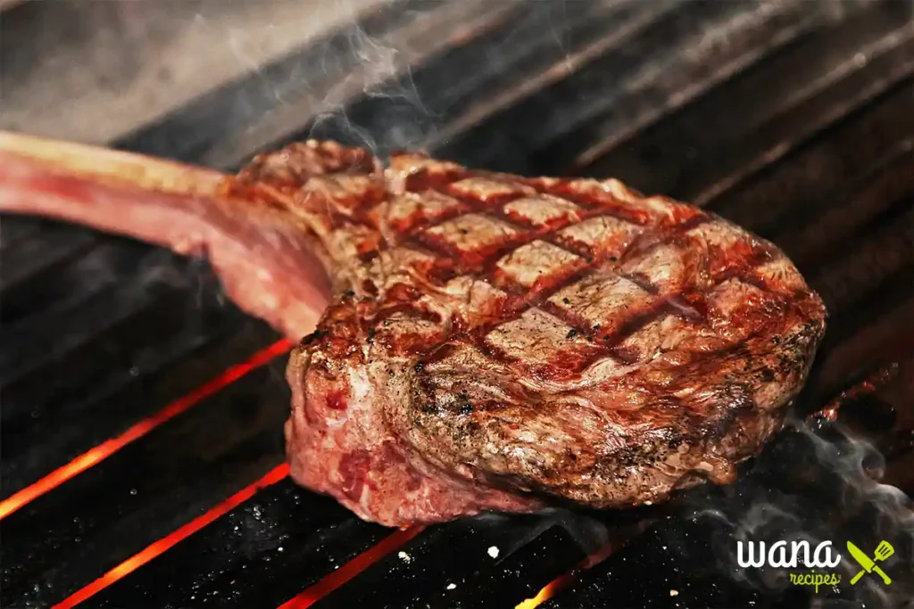 Juicy tomahawk steak grilling on a pellet grill with perfect grill marks.